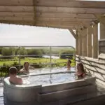 Colleagues relaxing together in an outdoor hot tub overlooking the North Cornwall countryside during a corporate wellness day at Little Pig Wellness.