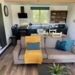 Open-plan self-catering lodge with fully equipped kitchen and comfortable living area at Little Pig Wellness near Bude, North Cornwall.